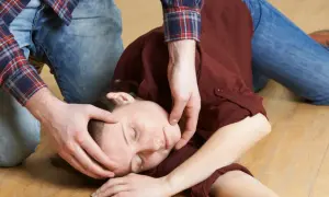 Osoba w pozycji bocznej bezpiecznej, z ręką pod głową, na podłodze.