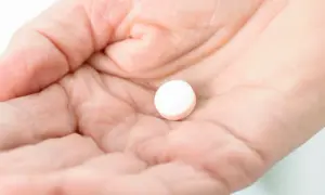 Dłoń trzyma białą tabletkę. Czy paracetamol podnosi ciśnienie? To pytanie nurtuje wiele osób.