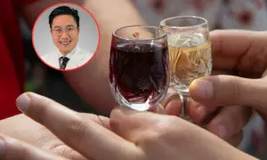 Lekarz w okularach patrzy na dwa kieliszki z alkoholem.