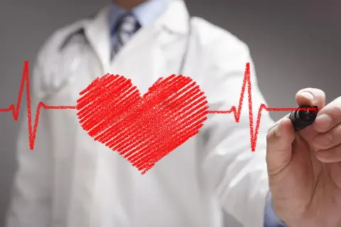 Lekarz rysuje serce i linię EKG. Może to symbolizować troskę o zdrowie serca, a nawet pomoc w radzeniu sobie ze stresem, jak Nebilet na uspokojenie.