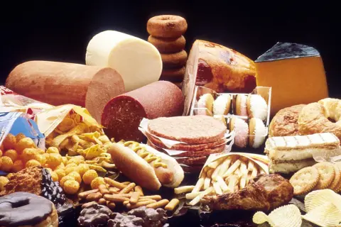 Stół ugina się od niezdrowych przysmaków: kiełbasy, sery, hamburgery, frytki, pączki i ciastka. Wiele z tych produktów zawiera tłuszcze trans.