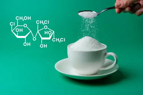 Struktura chemiczna sukralozy obok filiżanki cukru. Dowiedz się, sukraloza co to jest i jak działa.