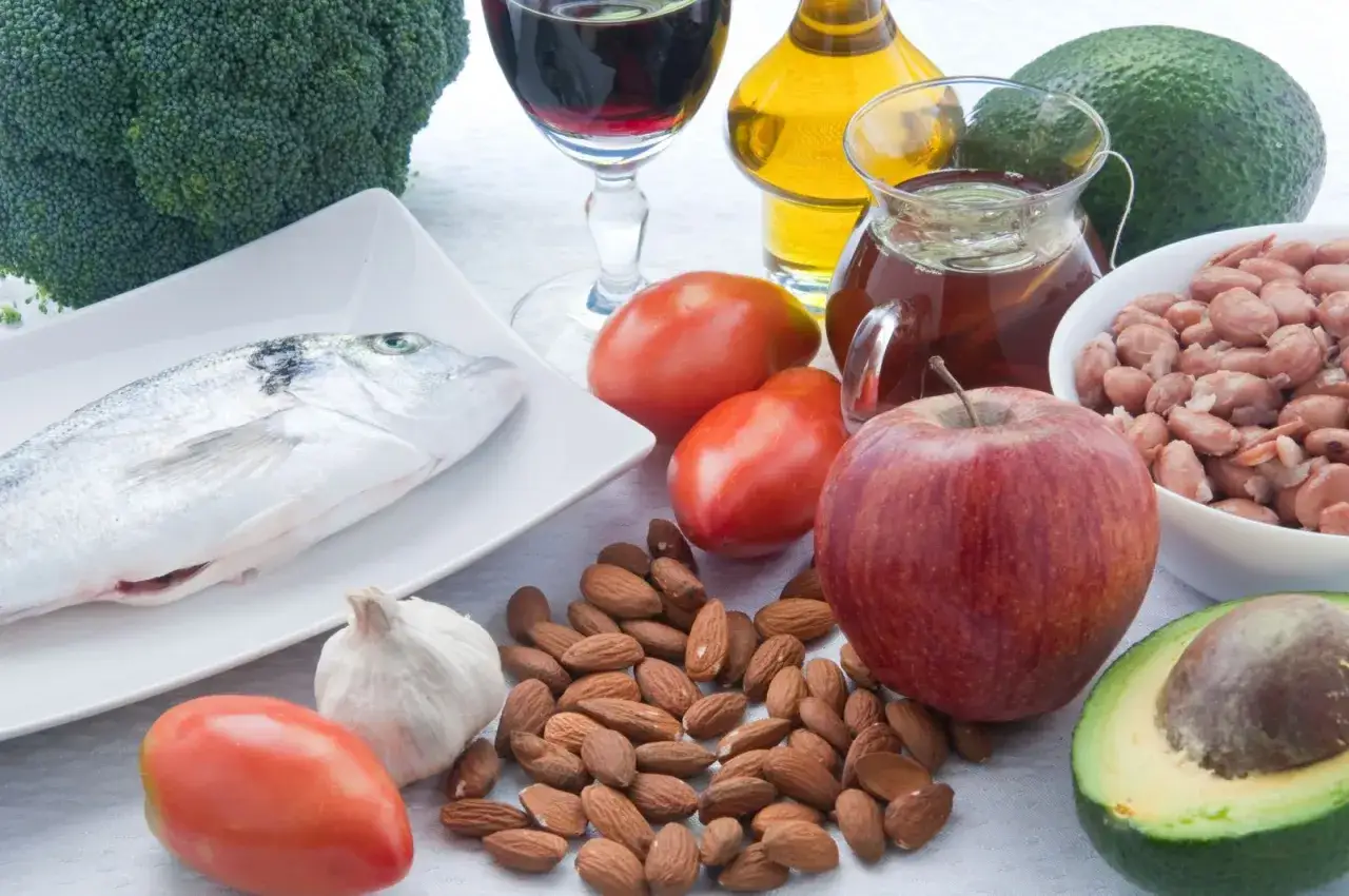 Zdrowe składniki na dieta niskocholesterolowa: ryba, brokuły, awokado, jabłko, migdały, pomidory, czosnek, fasola, oliwa z oliwek i czerwone wino.