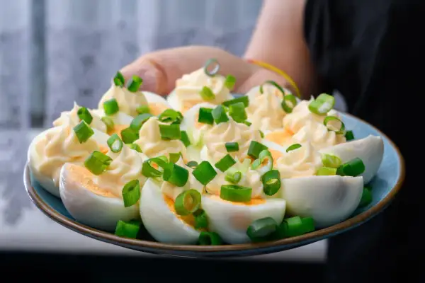 Jajka faszerowane, ozdobione majonezem i szczypiorkiem. Czy jajka są zdrowe? To pyszna przekąska!